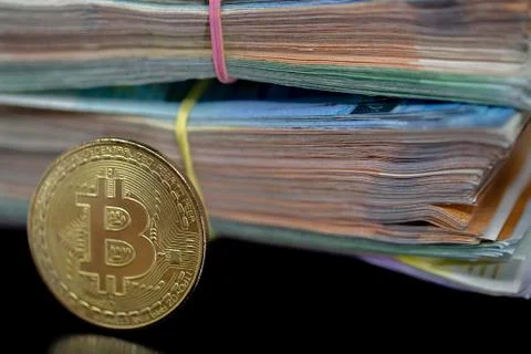 Bitcoin token on black with reflection, with a big pile of euro banknote money Stock Photos