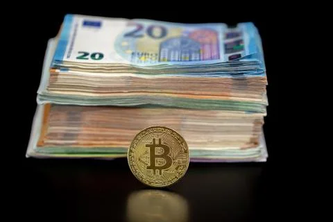 Bitcoin token on black with reflection, with a big pile of euro banknote money Stock Photos