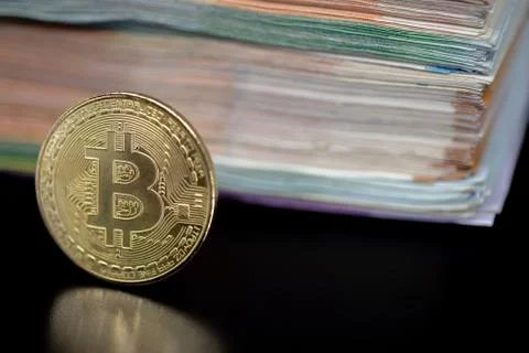 Bitcoin token on black with reflection, with a big pile of euro banknote money Stock Photos