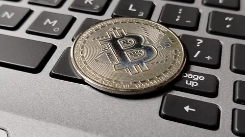 A Bitcoin token resting on a computer keyboard, symbolizing cryptocurrency inves Vídeos de archivo 340398463