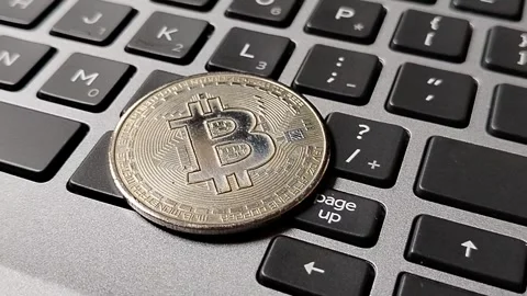 A Bitcoin token resting on a computer keyboard, symbolizing cryptocurrency inves Stock-Footage 340398464