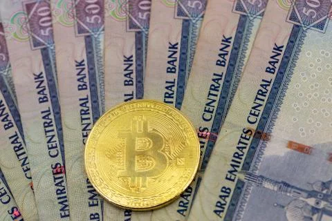 Bitcoin token on top of Dubai, dirham banknotes money. Stock Photos