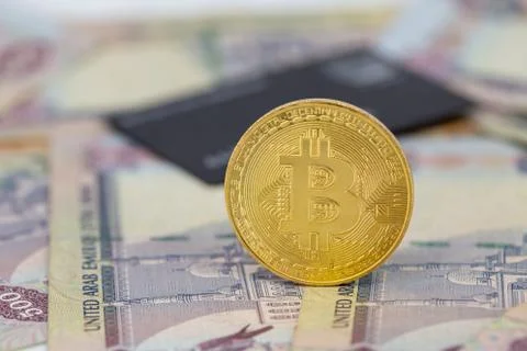 Bitcoin token on top of Dubai, dirham banknotes money with black credit card. Stock Photos