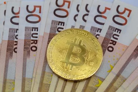 Bitcoin token on white background, on top of many euro banknotes money.  Stock Photos