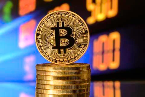 Bitcoin on top of Money stack, against blurry background. Stock Photos
