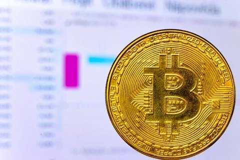 Bitcoin virtual currency in front of a screen with currency movement charts Stock Photos