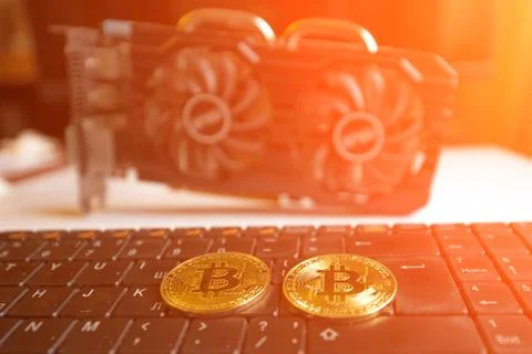 Bitcoins on a computer keyboard in bright light against the background of a c Stock Photos
