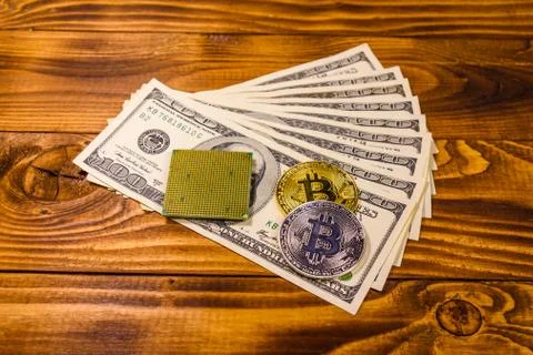 Bitcoins, microprocessor and one hundred dollar bills on wooden table Stock Photos