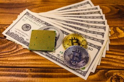 Bitcoins, microprocessor and one hundred dollar bills on wooden table 스톡 사진