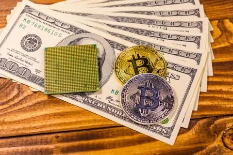 Bitcoins, microprocessor and one hundred dollar bills on wooden table Foto stock