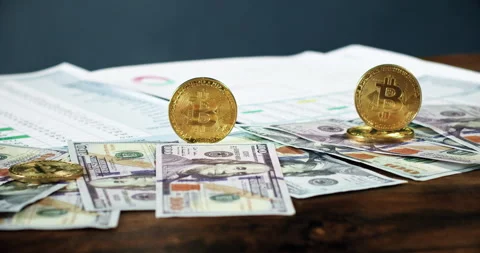 Bitcoins stand edge-on on backlit dollar bills Stock Footage 246501585