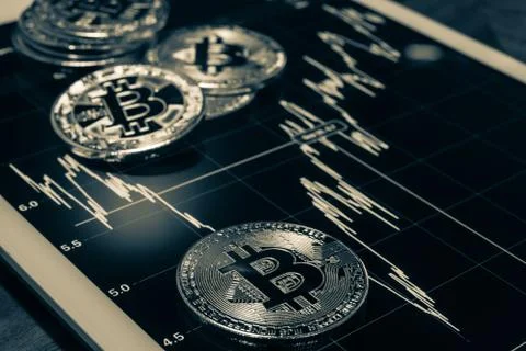 Bitcoins on tablet showing performance graph, black and white. Stock Photos