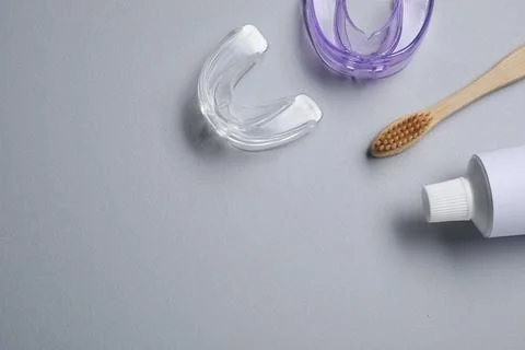 Bite correction. Toothpaste, brush and dental mouth guards on grey backgrou.. Stock Photos