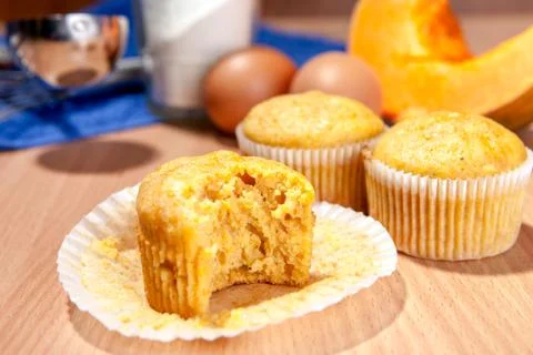Bite-off cupcake, pumpkin and baking kitchenware on table Stock Photos
