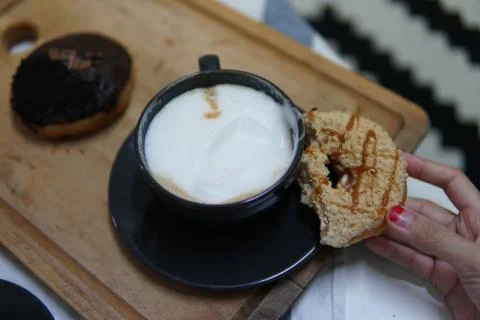 Bite doughnut with coffee at the background Stock Photos