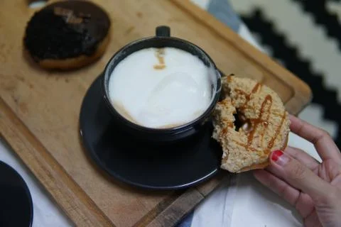 Bite doughnut with coffee at the background Stock Photos