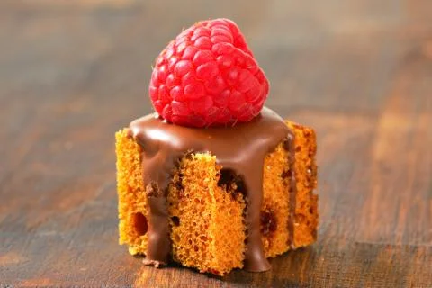Bite-sized gingerbread square with liquid chocolate and fresh raspberry on to Stock Photos