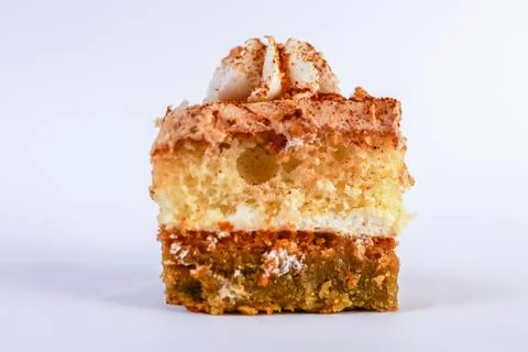 Bite-sized square slice of layered vanilla sponge cake topped with a neat swirl Stock Photos