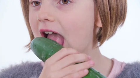 Biting into a big cucumber and a young girl likes it Stock Footage 83725371