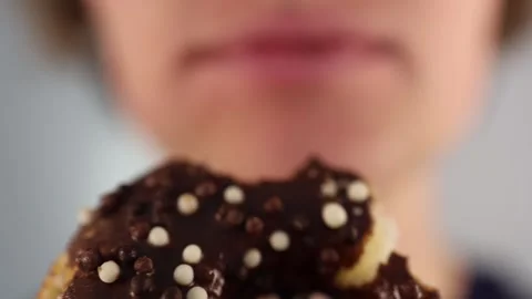 Biting into chocolate donut with missing teeth clearly visible in a dramatic clo Stock Footage 312202338