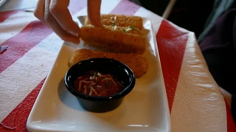 Biting deep fried mozzarella cheese sticks dipping into marinara sauce Stock Footage 91755686