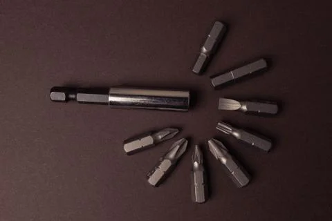 Bits bits for tightening screws of different sizes on a brown background. Foto stock