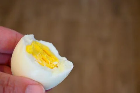 Bitten boiled egg in hand close-up Photos