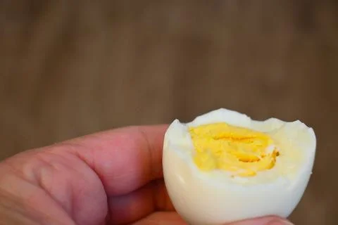 Bitten boiled egg in hand close-up Fotos Stock