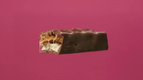 Bitten chocolate spin on isolate pink background. The unpacked bar is spinning Stock Footage 135552498