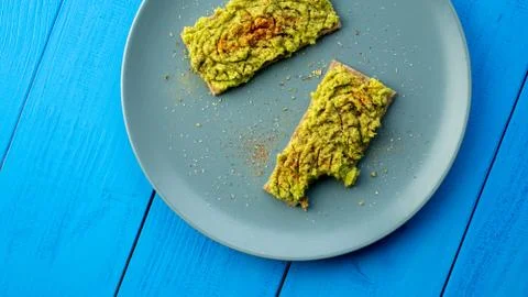 Bitten crispbread with avocado spread are on a blue plate, top view Stock Photos