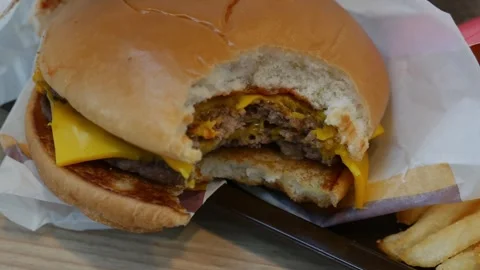 Bitten double cheeseburger with teeth marks Stock Footage 325478904