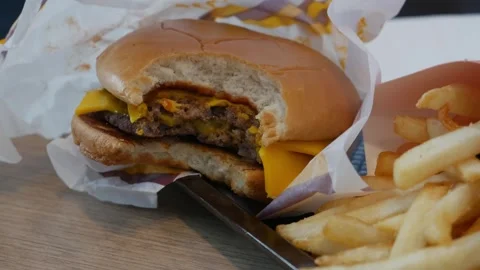 Bitten double cheeseburger with teeth marks Stock Footage 325478914