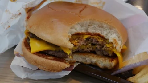 Bitten double cheeseburger with teeth marks Stock Footage 325965615