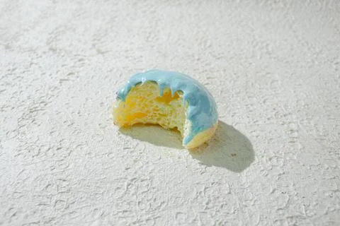 Bitten mini donut with a bite mark visible, set against a textured white ba.. Stock Photos
