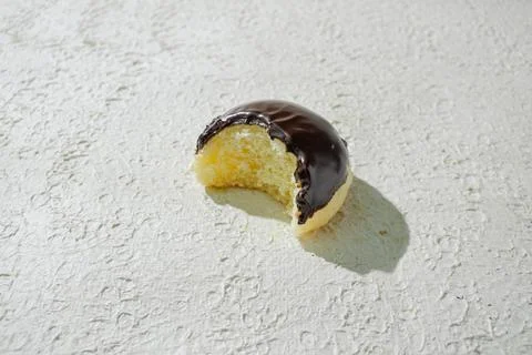 Bitten mini donut with a bite mark visible, set against a textured white ba.. Stock Photos