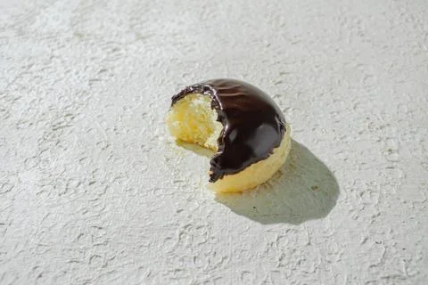 Bitten mini donut with a bite mark visible, set against a textured white ba.. Stock Photos