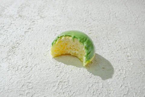 Bitten mini donut with a bite mark visible, set against a textured white ba.. Stock Photos