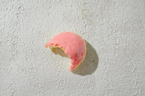 Bitten mini donut with a bite mark visible, set against a textured white ba.. Stock Photos