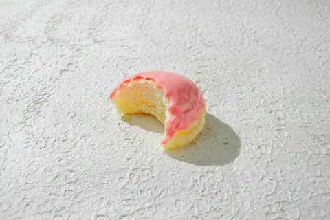 Bitten mini donut with a bite mark visible, set against a textured white ba.. Stock Photos