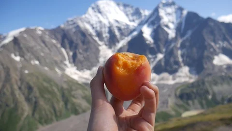 Bitten peach on a background of mountains and glacier Stock Footage 127734706