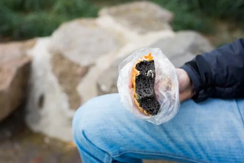 A bitten piece of black colored bread in a male hand Stock Photos