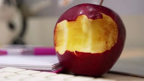 Bitten red apple on office desk Stock Footage 334409802