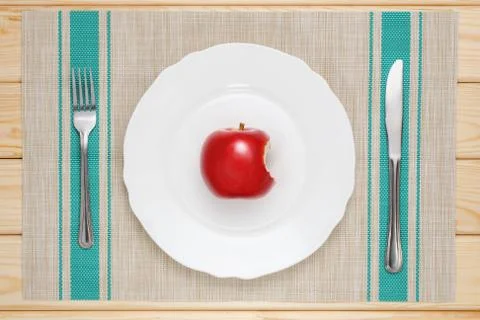 Bitten red Apple on a white plate Stock Photos