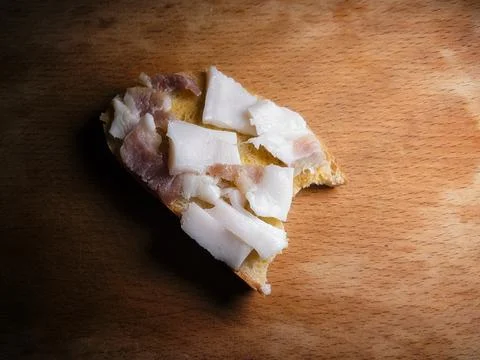 Bitten white bread with lard, on a dirty wooden board Stock Photos
