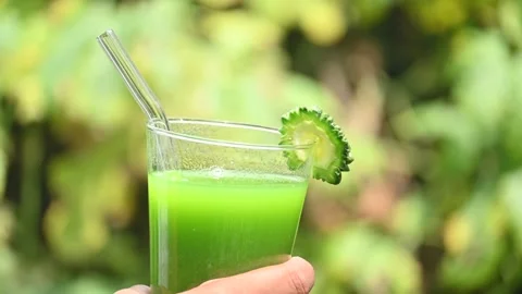 Bitter gourd or bitter melon juice on a blurry green background. Stock Footage 330232429