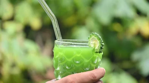 Bitter gourd or bitter melon juice on a blurry green background. 库存影片 330232497