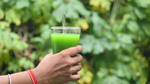 Bitter gourd or bitter melon juice on a blurry green background. Видео 330232628