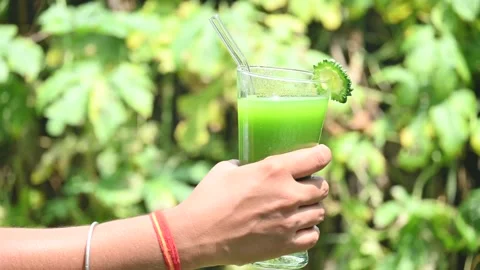 Bitter gourd or bitter melon juice on a blurry green background. 库存影片 330232645