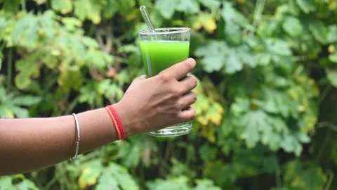 Bitter gourd or bitter melon juice on a blurry green background. 库存影片 330232655