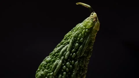 A bitter gourd rotating on black background close-up, a vegetable often used as Stock Footage 275844376